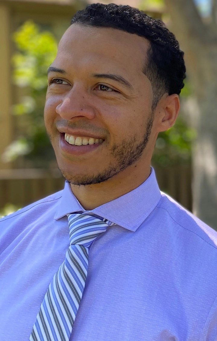 Photo of Jamil Bashir, MLT MBA Prep and MBA Professional Development Fellow. Jamil is photographed outdoors, wearing a light blue collared shirt and striped tie.